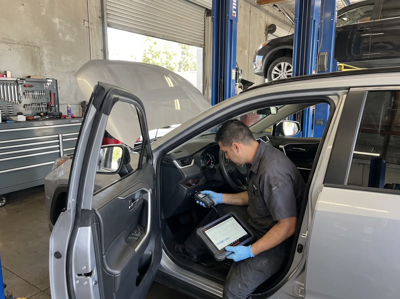 Mechanic reading live data with an OBD-II scan tool and a tablet in a Toyota RAV4