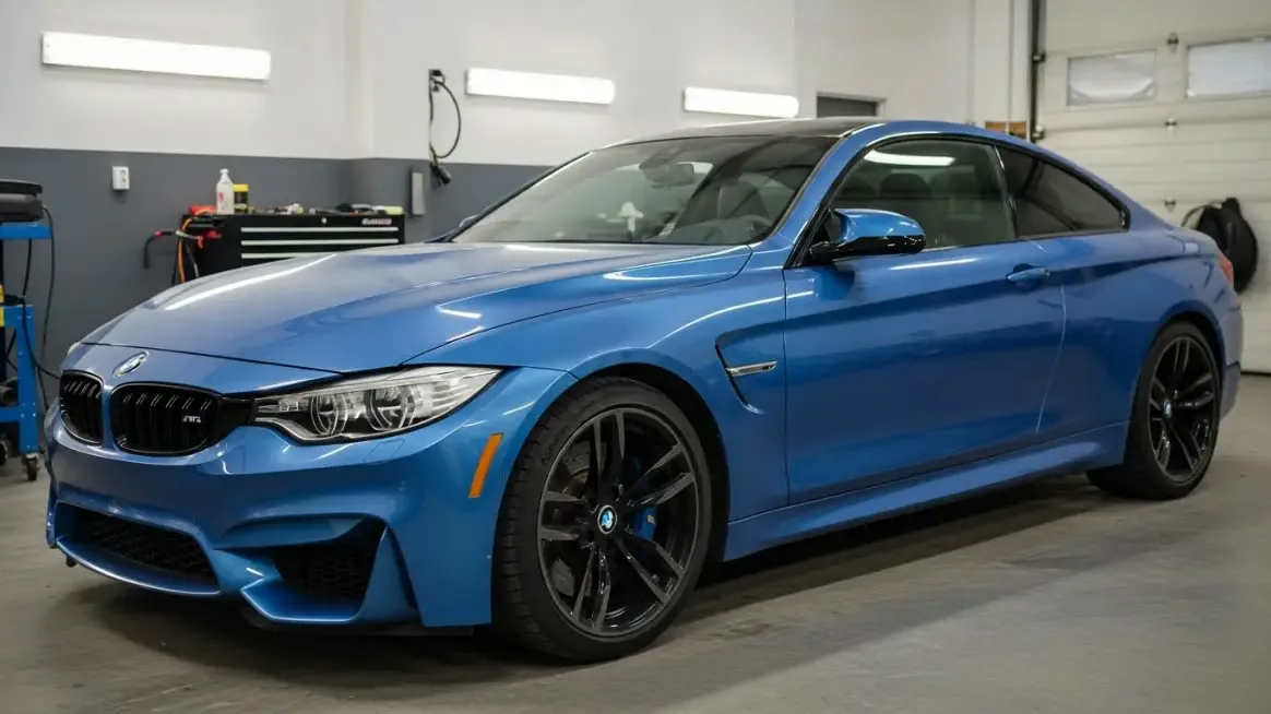 Blue BMW M4 coupe parked in a workshop before a vinyl wrap